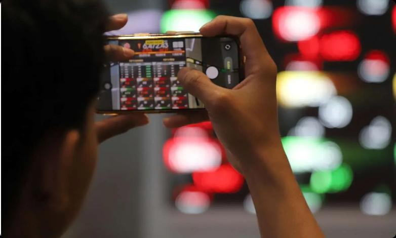 Investor memotret informasi perdagangan melalui ponsel